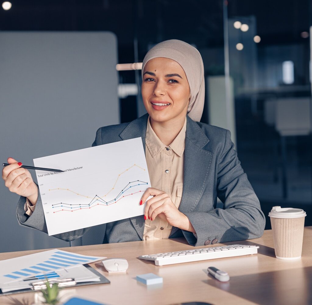 smiling muslim businesswoman in hijab shows a grap amh74w7